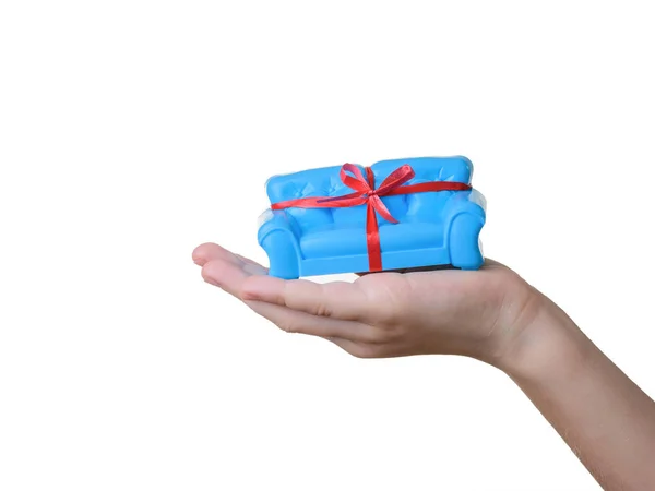 Blue sofa with red ribbon in baby's left hand isolated on white. Unusual gift. — Stock Photo, Image