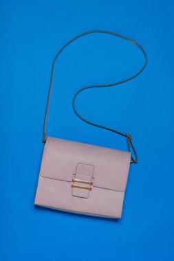 Mavi arka planda hafif deri kadın çantası. Modern kadın deri aksesuarı. Düz yatma.