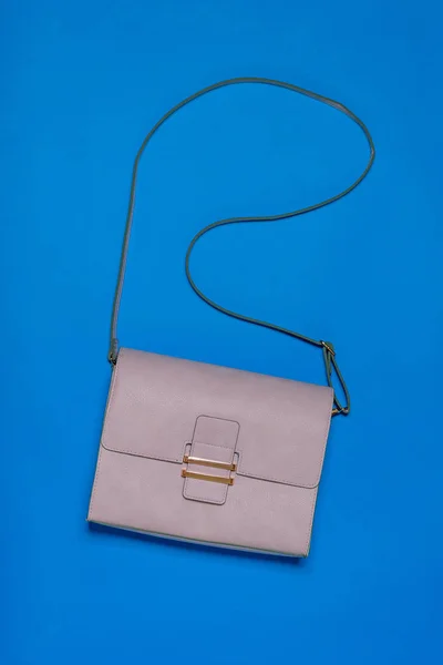 Light leather women's bag on blue background. Modern women's leather accessory. Flat lay. — Stock Photo, Image