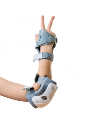 Çocuğun sağ elinde kalkanlar, beyaz bir arka planda izole edilmiş bir zafer işareti gösterir. Şok koruması için aksesuarlar.