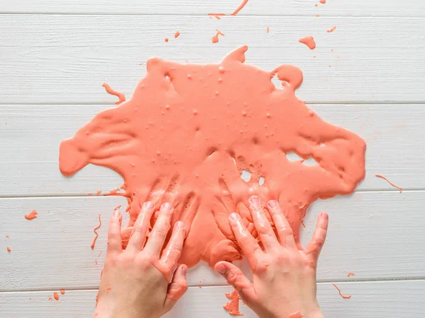 Ребенок окунул руки в оранжевую слизь . — стоковое фото