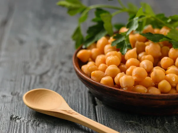 Branche de persil sur un bol avec des pois chiches bouillis sur une table noire . — Photo