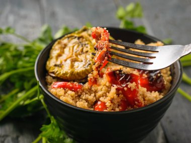 Haşlanmış Quinoa ve pişmiş sebze salatası ile siyah bir kapta bir demir çatal. Vejetaryen yemek. Doğal bitki yiyeceği. Yukarıdan görünüm.
