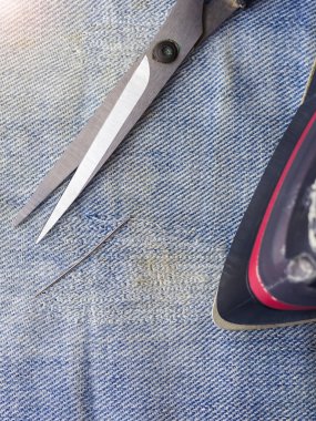 Makas, iğne ve iplik ve yırtık kot un üzerinde bir ütü. Evde kot tamiri.