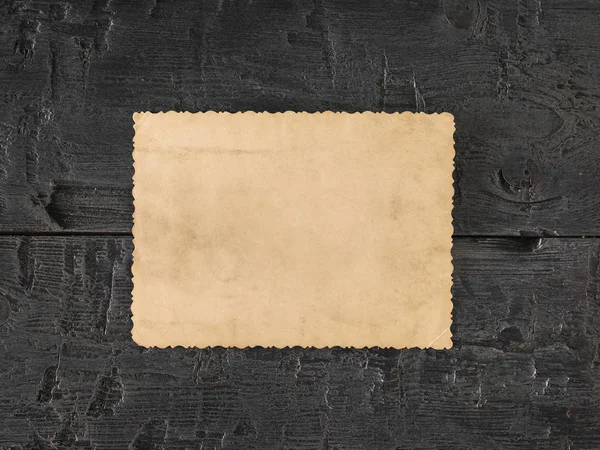 A sheet of old paper on a black wooden table. Retro writing paper. Flat lay.