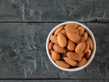 Siyah ahşap masa üzerinde badem ile Seramik beyaz Fincan. Vejetaryen yemekleri. Düz yatıyordu.