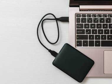 Işık Masası'ndaki dizüstü bilgisayara bağlı harici sabit disk. Düz yatıyordu. Yedekleme depolama kavramı.