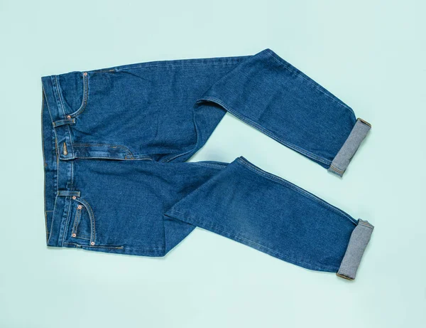 Crumpled men's jeans with cuffs on a blue background. Flat lay.