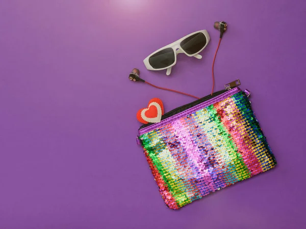 Красочная женская сумка в очках и наушниках на фиолетовом фоне. Модный женский аксессуар. Плоский лежал . — стоковое фото