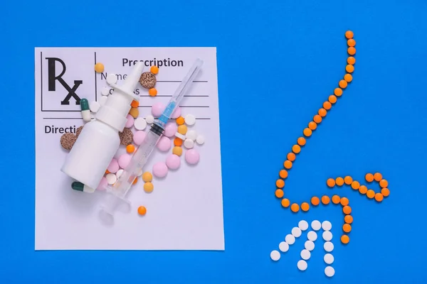 Doctor's appointment form with medicines and a figure of the nose of the tablets on a blue background.The concept of treatment of diseases of the nose and allergies. Flat lay.