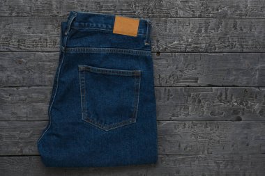 Koyu ahşap bir masada erkek mavi kot pantolon. Klasik kot giyim. Düz yatıyordu.