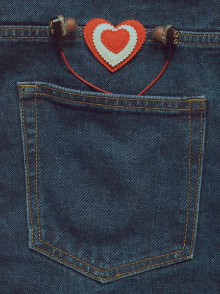 Getöntes Bild der Jeanstasche mit Kopfhörern und einem rot-weißen Herz. — Stockfoto