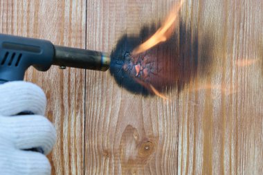 Bir brülör ile bir eldiven el ahşap paneller ateş gerçekleştirir. Ahşap yüzey yangını tedavisi.