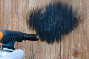 Adam vintage işleme için gaz brülör ahşap panoları yakar. Ahşap yüzey yangını tedavisi.