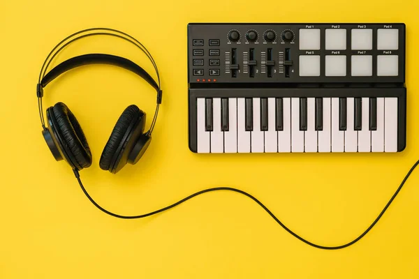 Koptelefoon en muziek mixer op fel gele achtergrond. Het concept van de organisatie van de werkplek. — Stockfoto