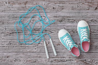 Turkuaz spor ayakkabılar ve ahşap zeminde yüksek hızlı atlama ipi. Spor tarzı. Düz yatıyordu.