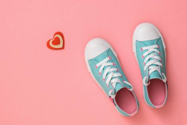 Turkuaz spor ayakkabılar ve pembe arka plan üzerinde kırmızı beyaz bir kalp. Renk trendi 2019. Spor tarzı. Düz yatıyordu.