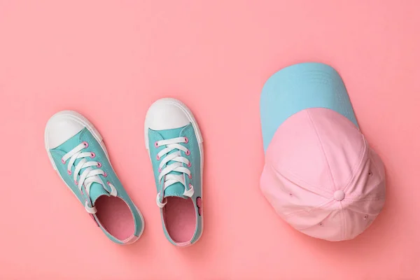 Turquoise shoes and turquoise cap on a pink background. Flat lay.