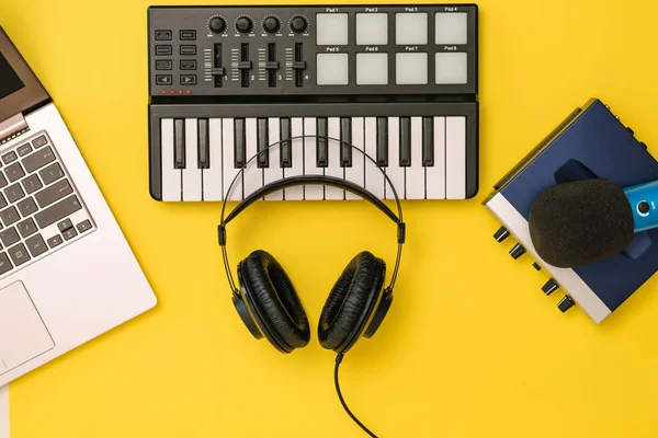 音乐混音器上的耳机、黄色背景上的笔记本电脑和声卡。工作场所组织的概念. — 图库照片