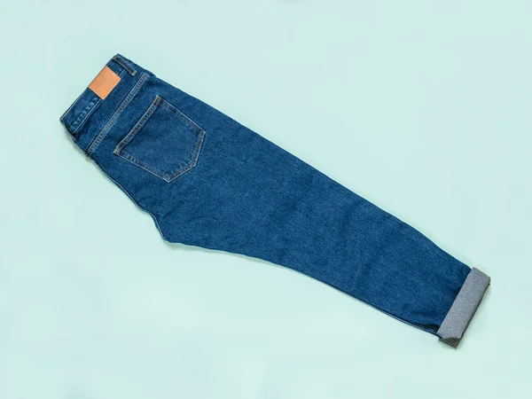 Keurig gestapelde blauwe jeans op een blauwe achtergrond. Platte lay. — Stockfoto