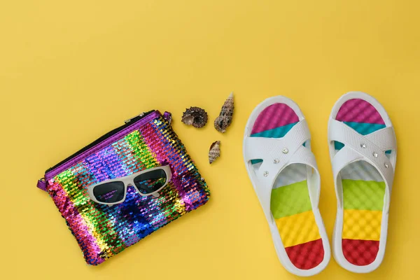 Zapatos coloridos para mujeres, conchas marinas, gafas de sol y una bolsa sobre un fondo amarillo brillante. El concepto de vacaciones de verano. Puesta plana . — Foto de Stock