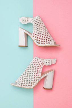 Yaz ayakkabıları mavi ve pembe arka plan üzerinde beyaz deriden yapılmış. Düz yatıyordu.