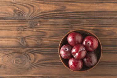Ahşap bir masa üzerinde olgun taze erik ile Kil kase. Düz yatıyordu.