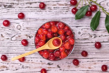 Wooden spoon in a Cup of cherry jam on a wooden table. Homemade jam from the fresh harvest of cherry berries. Flat lay. clipart
