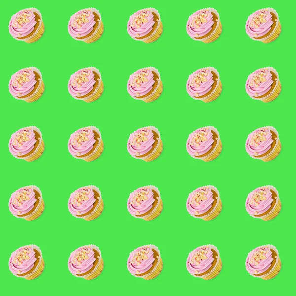 Pattern of a large number of cupcakes with pink cream on a green background. Minimalism. — Stock Photo, Image