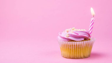 Berry krem ve pembe bir arka plan üzerinde bir mum ile Cupcakes.
