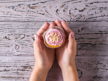 Çocuk tahta bir masada taze bir kek tutar.