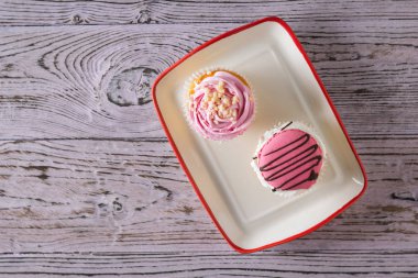 Ahşap bir masa üzerinde bir kase içinde iki cupcakes.