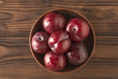 Tahta bir masa üzerinde olgun erik ile Kil kase. Düz yatıyordu.