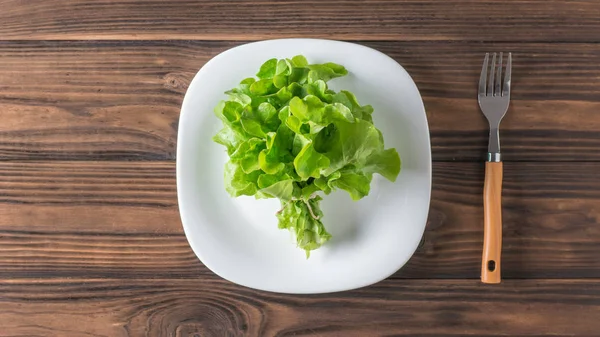 Garfo ao lado de tigela branca com salada fresca em mesa de madeira. Depósito plano . — Fotografia de Stock