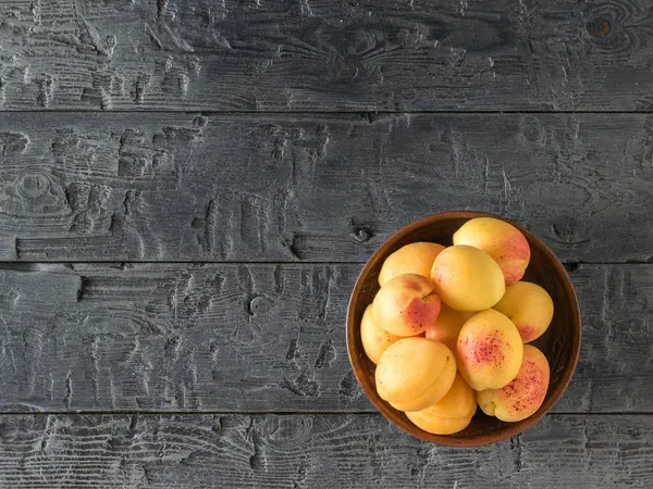 Bowl with fresh ripe apricots on a dark wooden table. — Stock Photo, Image