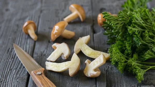 Нарезанные и целые грибы с ножом на деревянном столе . — стоковое фото