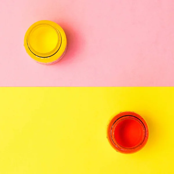 Frascos de pintura roja y amarilla sobre fondo amarillo y rosa. Kit creativo . — Foto de Stock