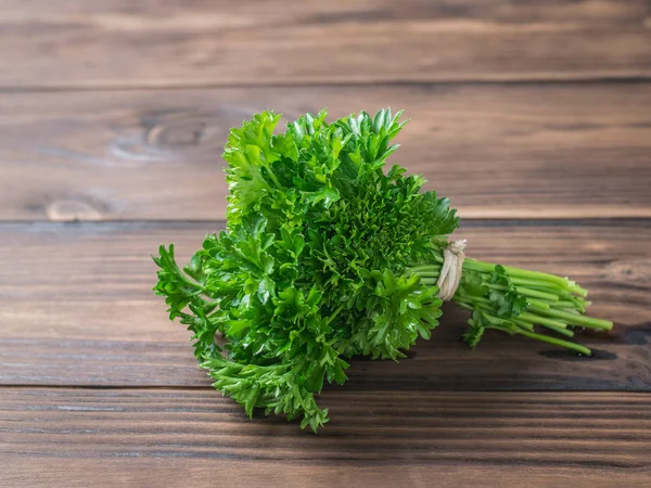 Tahta rustik bir masada bir demet taze maydanoz.