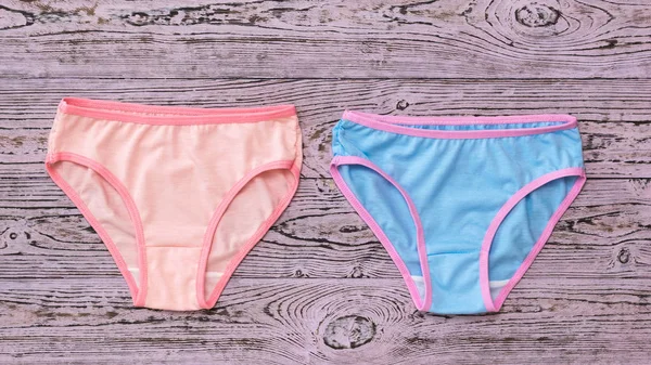 Stacked women's panties on a pink wooden background. Fashionable concept. Beautiful lingerie. The view from the top. — Stock Photo, Image