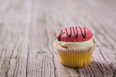 Ahşap bir masa üzerinde çikolata ile süslenmiş pembe kurabiye ile Cupcakes. Seçici odaklama.