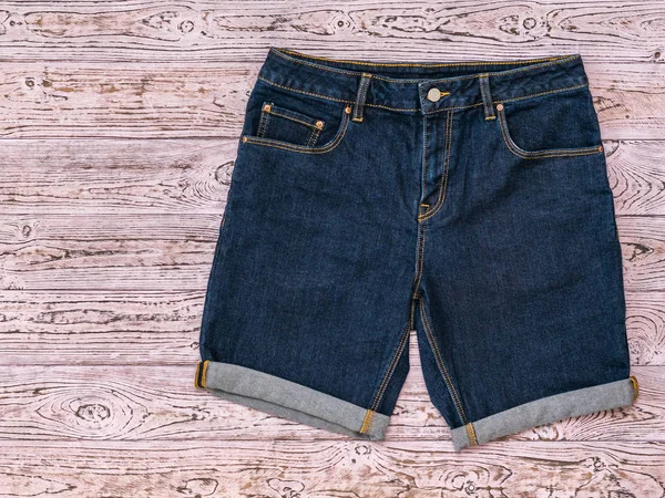 Blaue Jeans-Shorts auf rosa getöntem Holzgrund. Modische Unisex-Kleidung. — Stockfoto