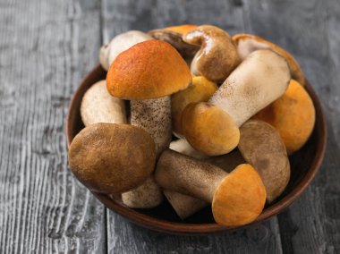 Ahşap bir masa üzerinde taze kesilmiş mantar ve aspen mantar ve kahverengi kap boletus ile Kil kase.