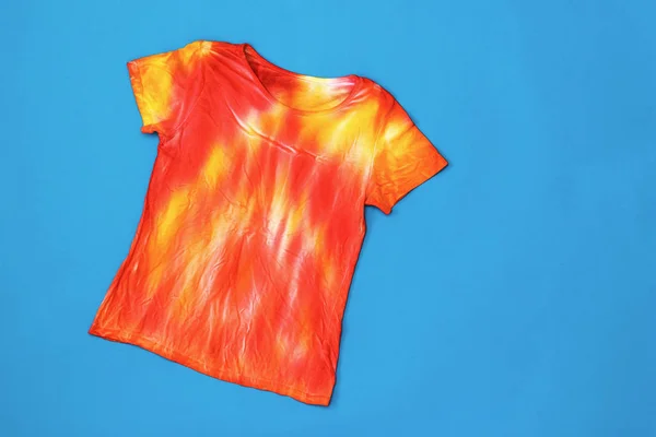 T-shirt in rood en geel in de stijl van tie dye op een donker blauwe achtergrond. Platte lay. — Stockfoto