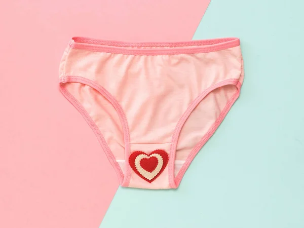 Pink women's panties with red heart on pink and blue background. Flat lay. — Stock Photo, Image