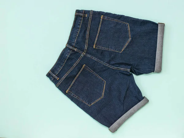 Niebieskie szorty dżinsowe na niebieskim tle. Modne ubrania Unisex. — Zdjęcie stockowe