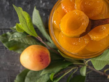 Bir kaşık ve yaprakları ile bir dal ile kayısı reçel. Üstteki görünüm.