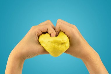 Heart made of slime by children's hands on a blue background. clipart