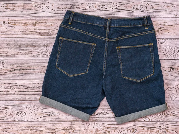 Lado inverso de los pantalones cortos de mezclilla sobre fondo de madera rosa. Ropa unisex de moda . —  Fotos de Stock