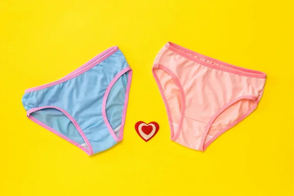 Blue and pink panties with a heart on a yellow background. The concept of meeting lovers. Underwear. The view from the top. — Stock Photo, Image