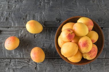 Bir kase ve ahşap bir masada büyük olgun kayısı.